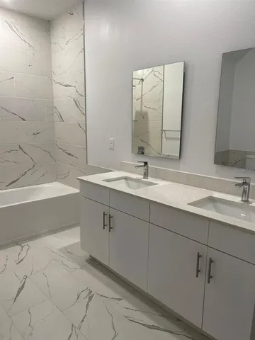 a bathroom with a double vanity sink mirror and a bathtub