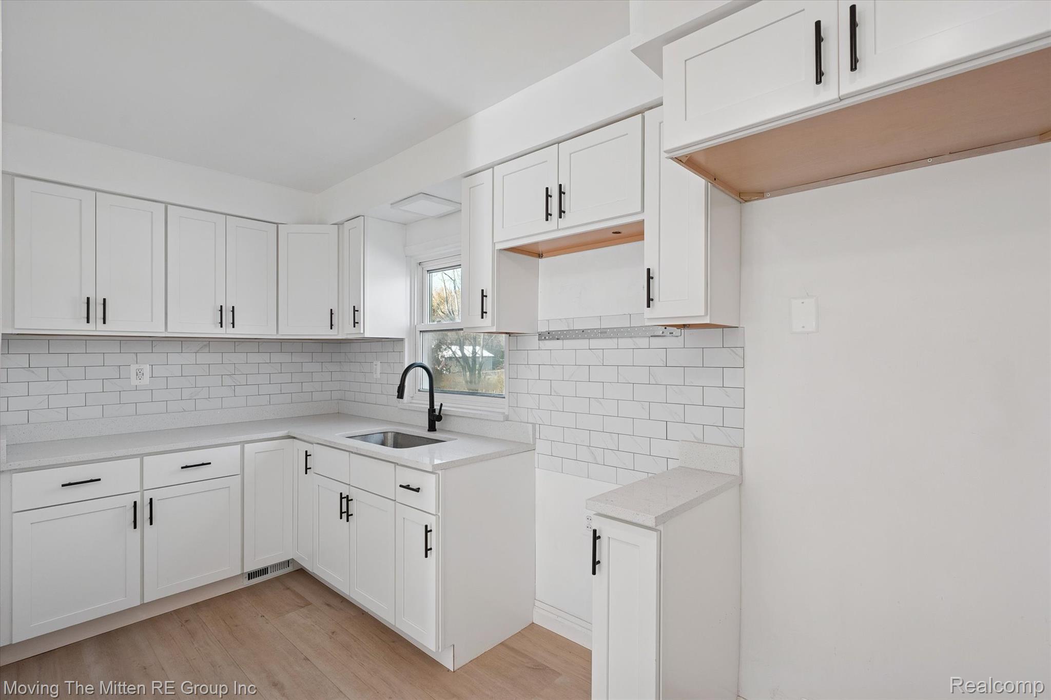 41190 Savage Road Belleville, MI 48111 - Photo 12 of 38 Kitchen with white cabinetry, light wood-type flooring, and backsplash