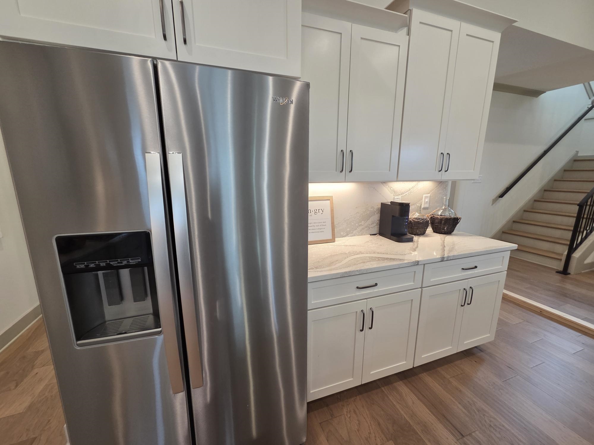 657 Mount Laurel Drive Collierville, TN 38017 - Photo 13 of 40 a kitchen with stainless steel appliances granite countertop a refrigerator a sink and white cabinets with wooden floors