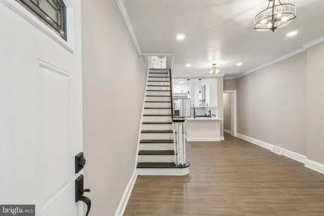 a view of a hallway with stairs and chandelier