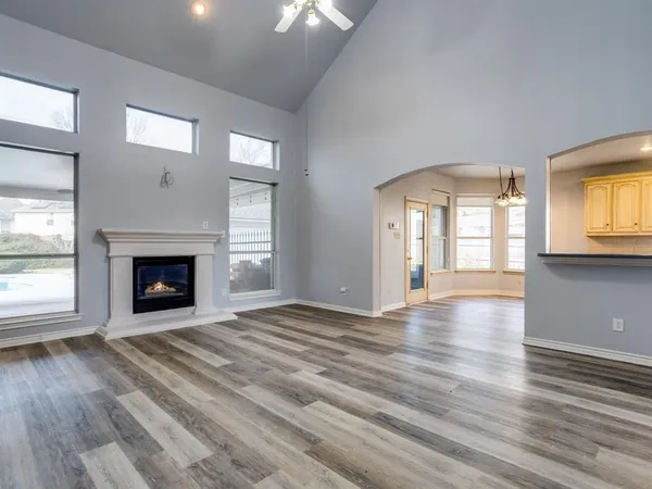a view of an empty room with wooden floor fireplace and a window