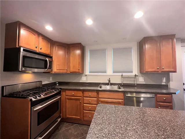 a kitchen with stainless steel appliances granite countertop a stove a sink dishwasher and a microwave