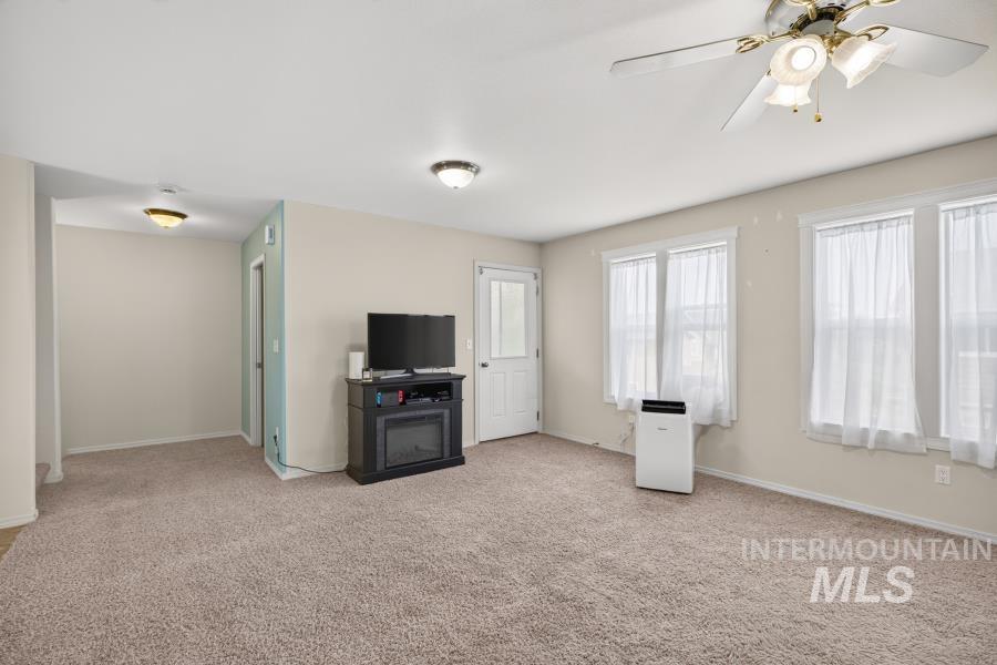 1337 Bristol Road Moscow, ID 83843 - Photo 5 of 28 Carpeted living area featuring multiple windows, a ceiling fan with integrated lighting, and a built-in electric fireplace unit