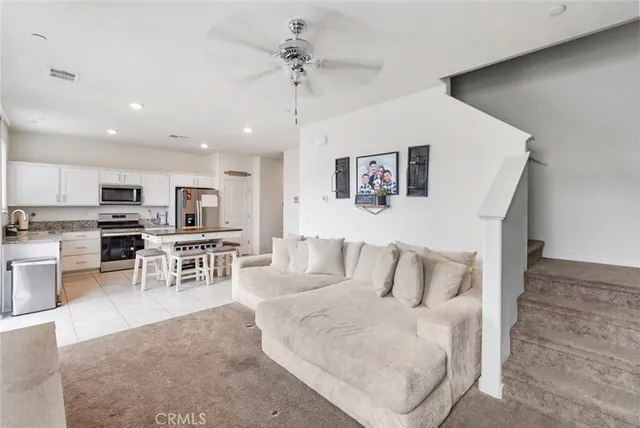 a living room with stainless steel appliances furniture and a kitchen view