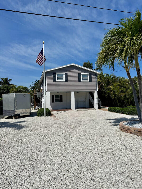 1109 76 Street, Unit OCEAN Marathon, FL 33050 - Photo 2 of 24 a front view of a house with a yard and garage