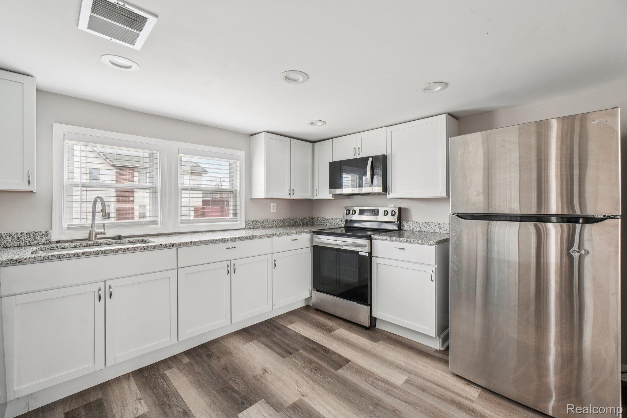 3822 Wabash Street Detroit, MI 48208 - Photo 8 of 17 Kitchen with stainless steel appliances, white cabinets, light wood-style floors, light stone counters, and recessed lighting