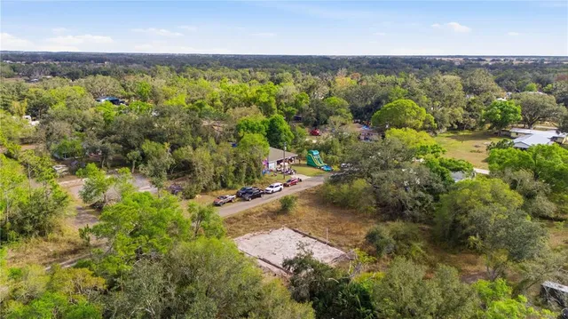 an aerial view of residential house with outdoor space and trees all around