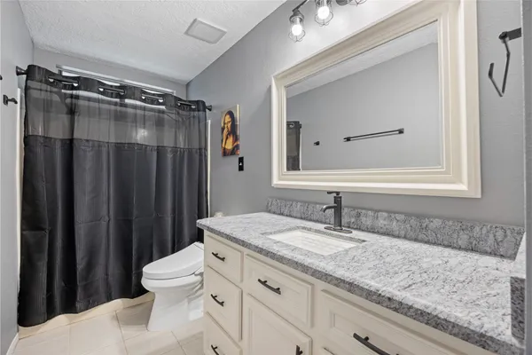 a bathroom with a granite countertop sink vanity mirror and toilet