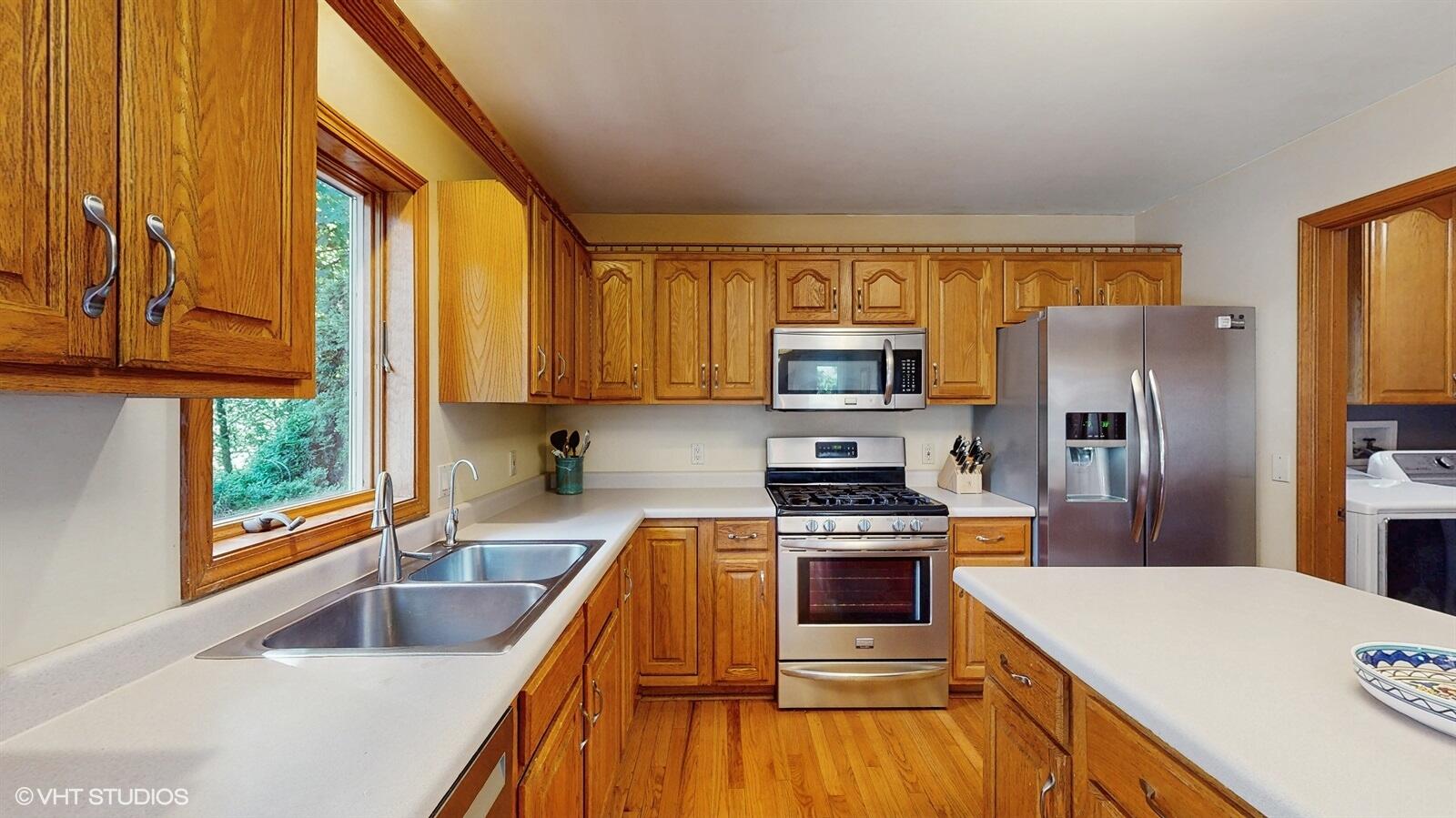 3908 Autumn Lane Valparaiso, IN 46385 - Photo 6 of 29 a kitchen with a refrigerator a stove top oven a sink and dishwasher with wooden floor