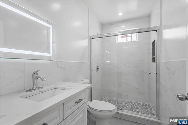 a bathroom with a shower sink vanity mirror and toilet