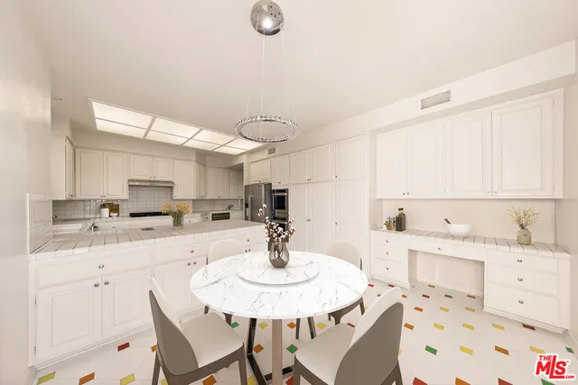 a kitchen with a sink a stove chandelier dining table and chairs