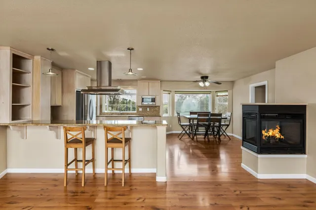 a kitchen with stainless steel appliances granite countertop a stove top oven a dining table and chairs with wooden floor