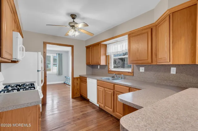 a kitchen with stainless steel appliances granite countertop a sink dishwasher and a stove with wooden floor