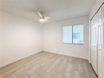 an empty room with a ceiling fan and a window