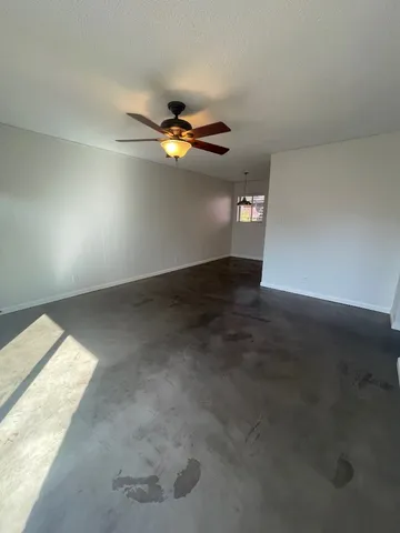 an empty room with a window and ceiling fan