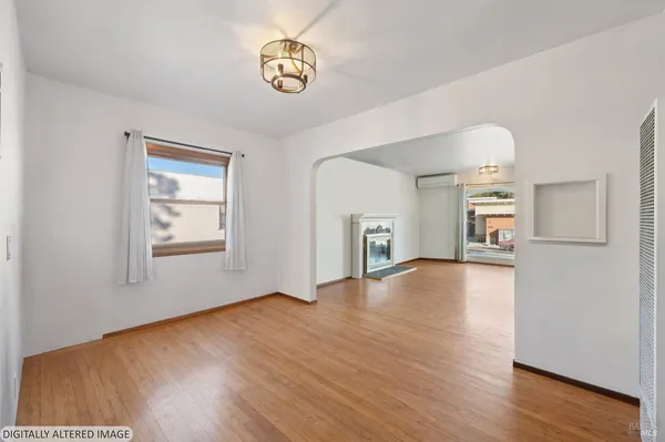 a view of an empty room with window and wooden floor