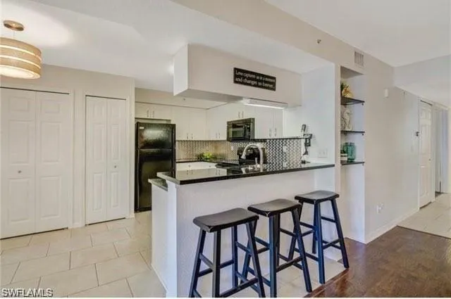 a kitchen with stainless steel appliances granite countertop a table chairs refrigerator and microwave