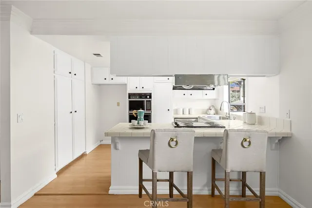 a kitchen with stainless steel appliances a white table chairs and a refrigerator