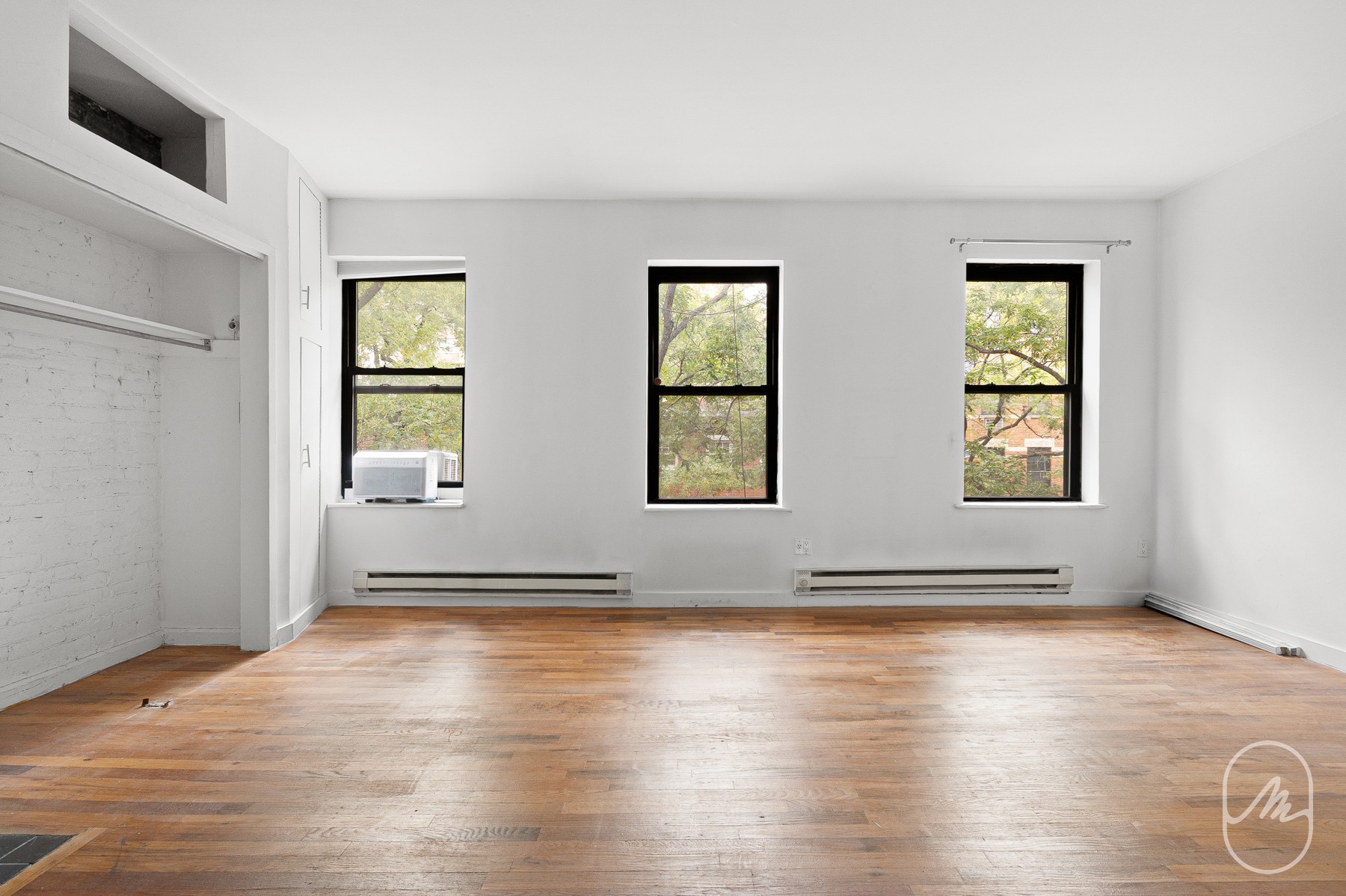an empty room with wooden floor and windows