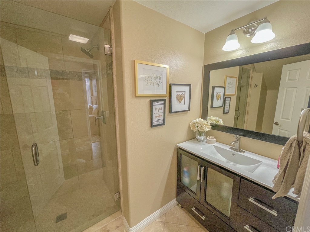 5381 Campania Way Fontana, CA 92336 - Photo 12 of 45 a bathroom with a granite countertop sink a mirror and a shower