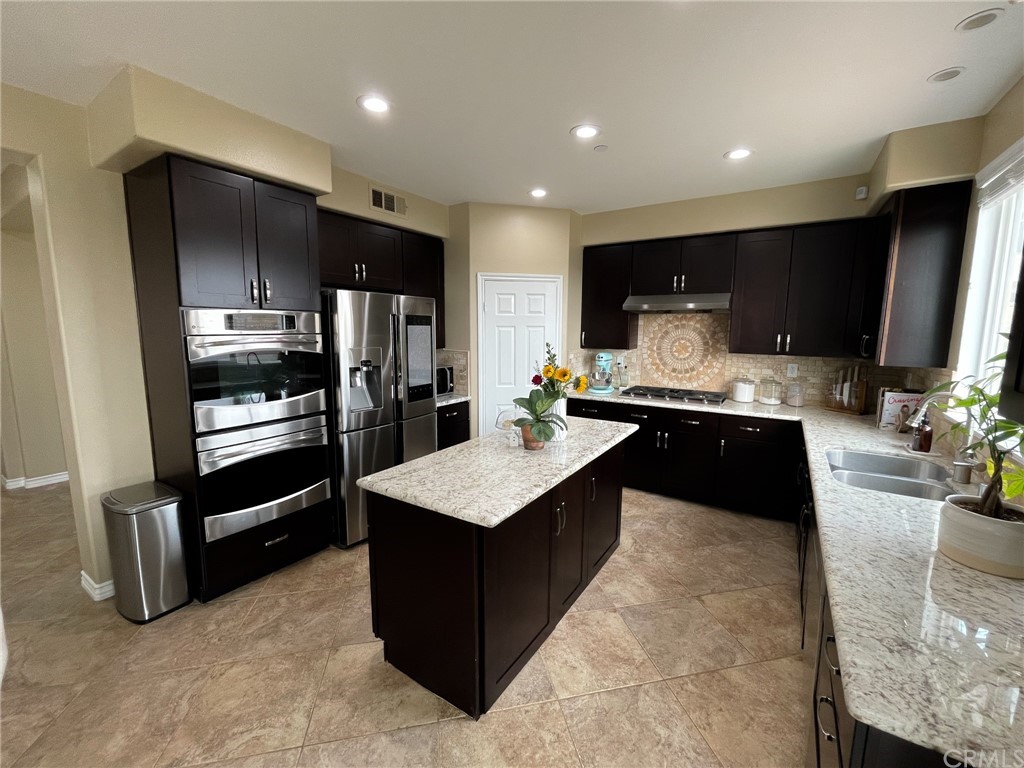 5381 Campania Way Fontana, CA 92336 - Photo 13 of 45 a large kitchen with stainless steel appliances kitchen island granite countertop a refrigerator and a stove top oven