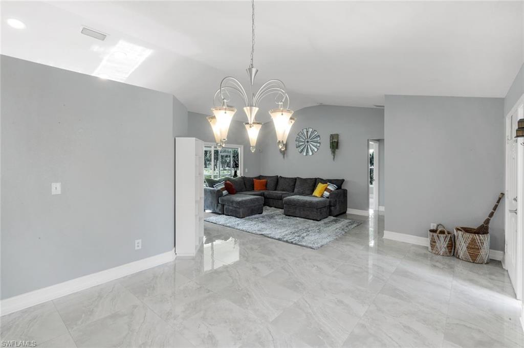 3780 12th Avenue Southeast Naples, FL 34117 - Photo 17 of 43 a living room with furniture a chandelier and a large mirror