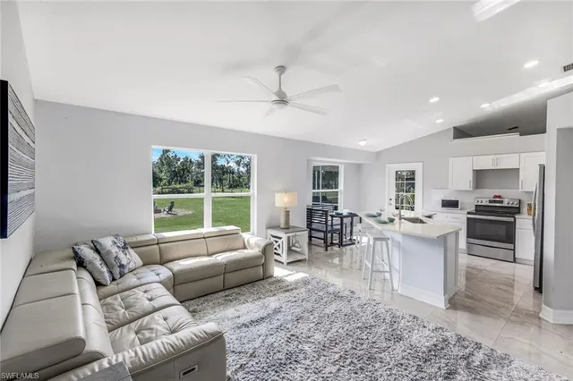 a living room with furniture a large window and a dining table
