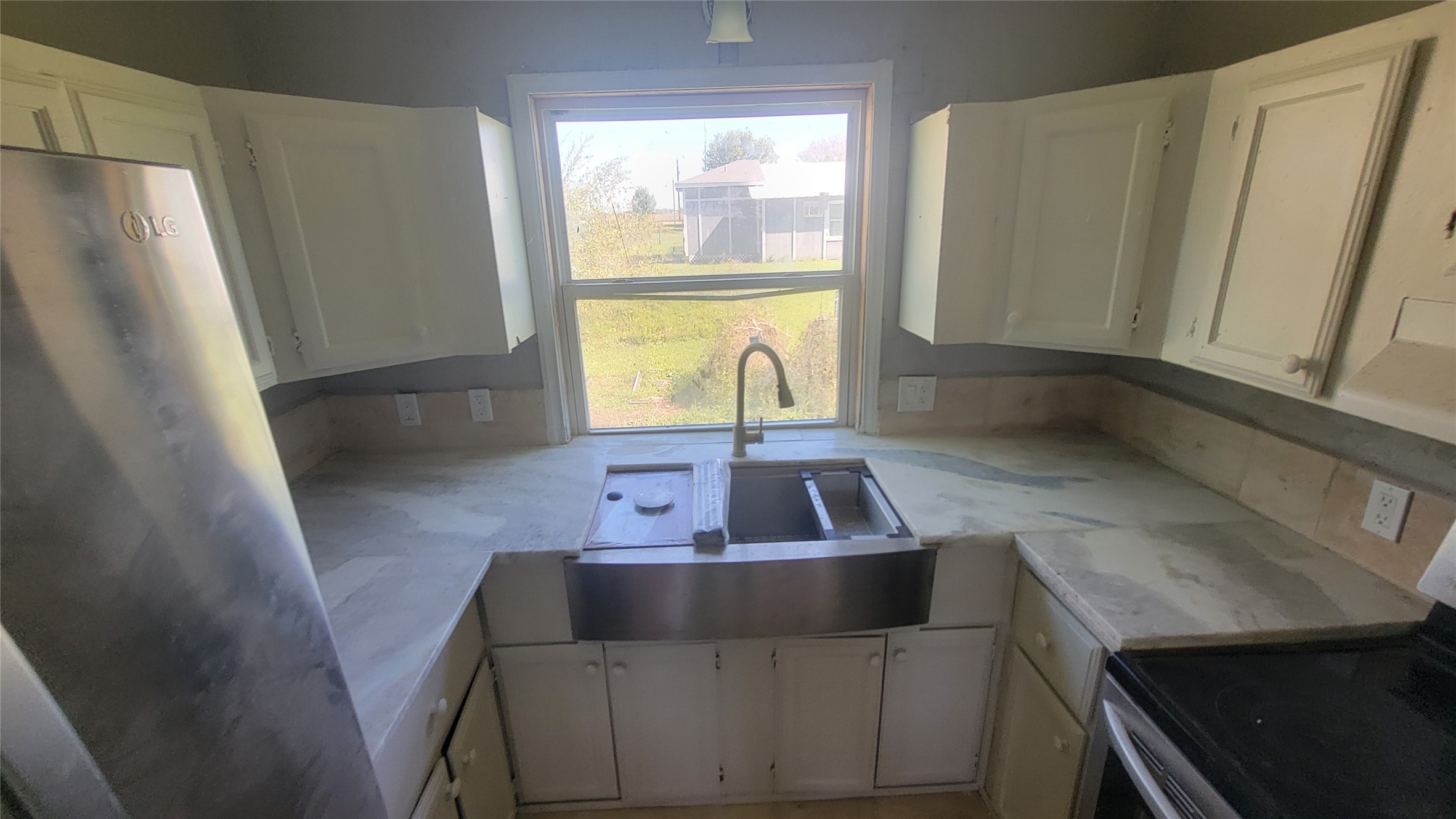 12018 Sandpiper Road Angleton, TX 77515 - Photo 35 of 48 This kitchen features a large window overlooking the backyard, white cabinetry, stainless steel appliances, and a farmhouse sink. It offers ample counter space and natural light for a bright, inviting atmosphere.