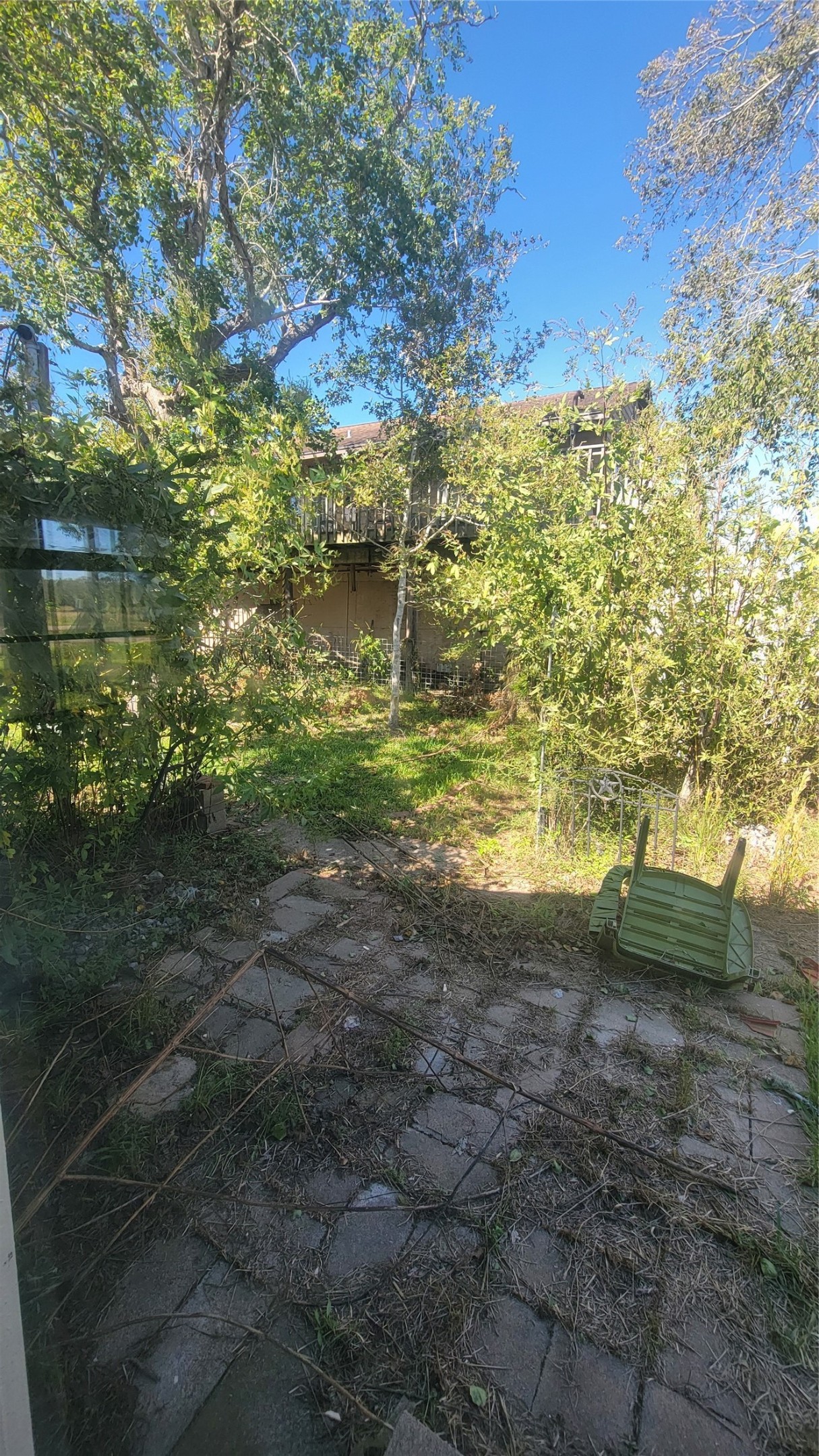 12018 Sandpiper Road Angleton, TX 77515 - Photo 38 of 48 The photo shows a backyard with a stone patio, surrounded by lush greenery and mature trees, offering a natural, private setting.