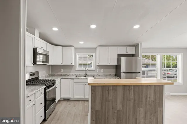 a kitchen with white cabinets a sink and stainless steel appliances