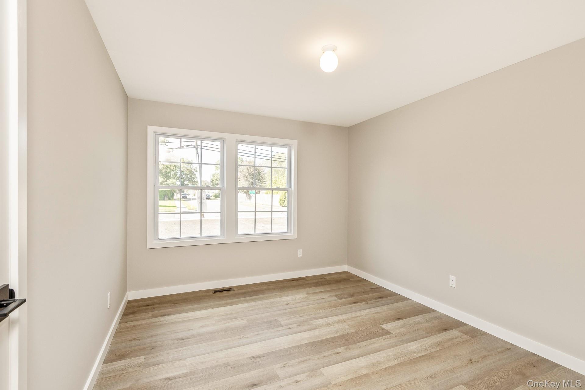 92 Park Street Blue Point, NY 11715 - Photo 14 of 32 an empty room with wooden floor and windows