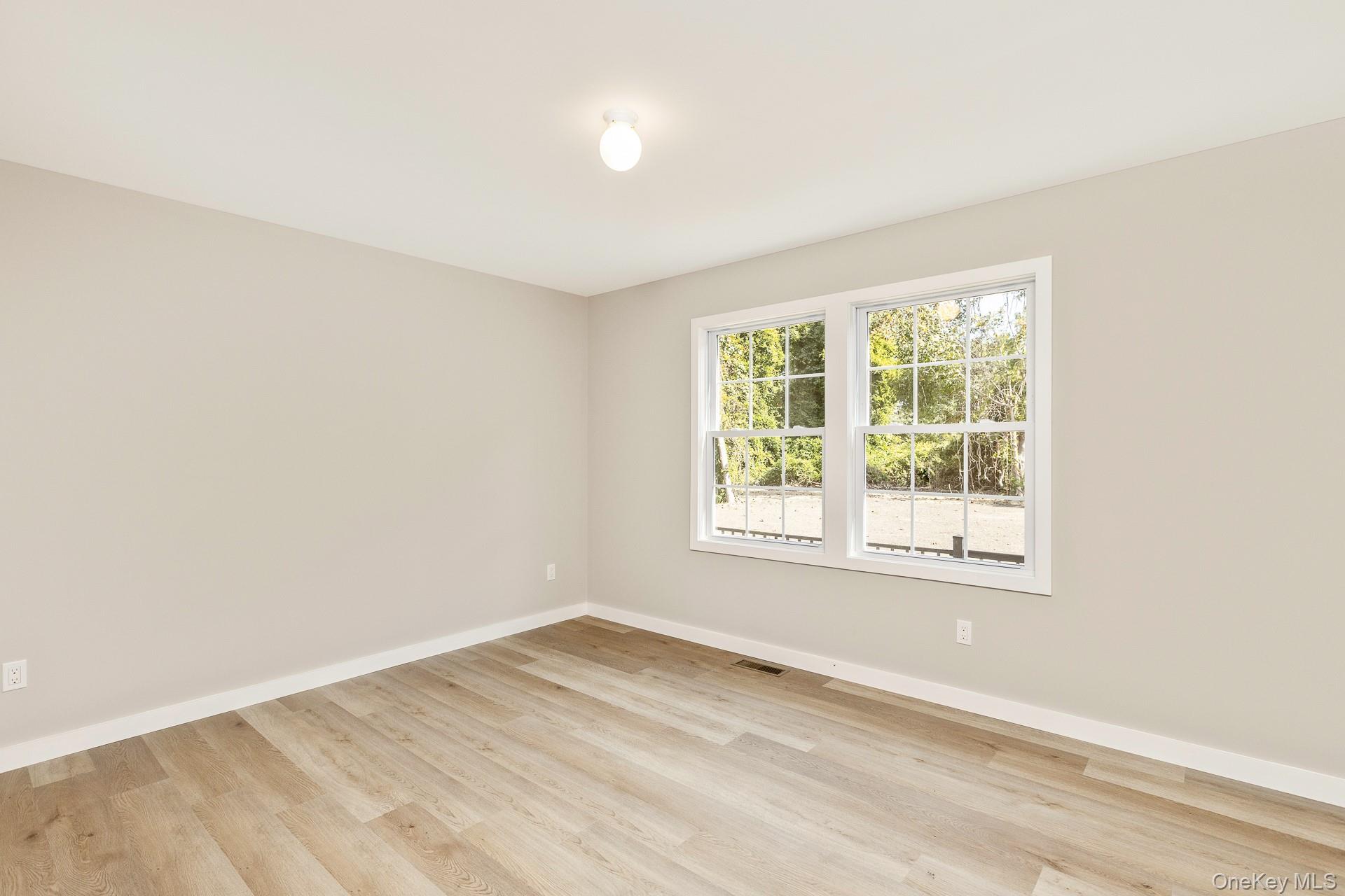 92 Park Street Blue Point, NY 11715 - Photo 15 of 32 an empty room with wooden floor and windows