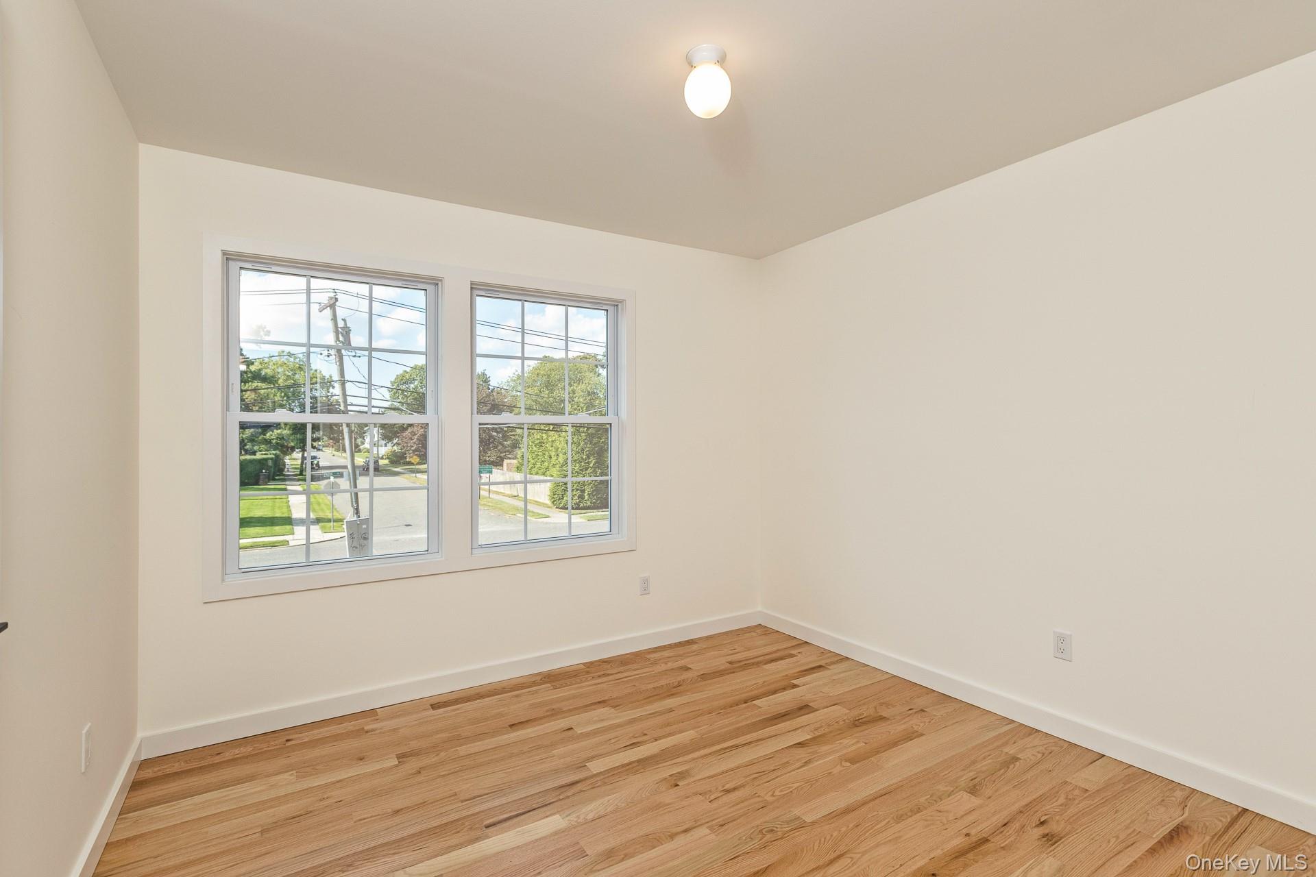 92 Park Street Blue Point, NY 11715 - Photo 28 of 32 an empty room with wooden floor and windows