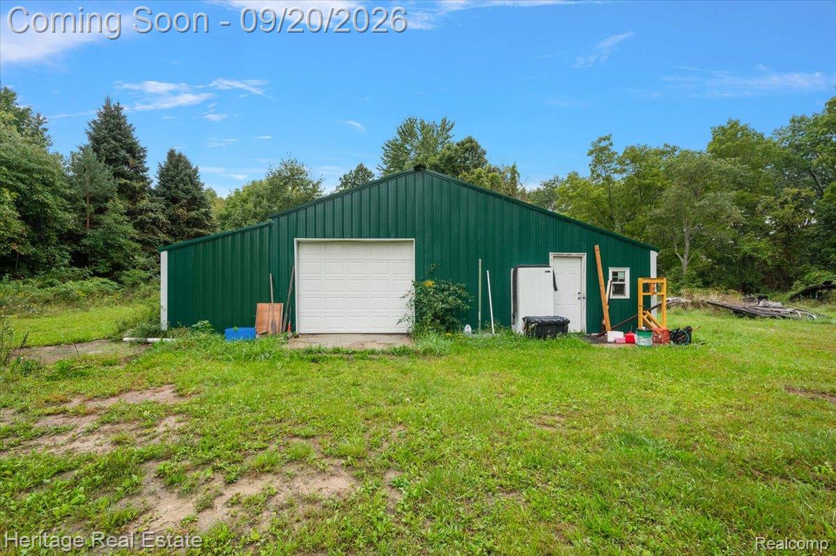 3337 Le Valley Road Columbiaville, MI 48421 - Photo 37 of 57 Green metal-sided structure with a white roll-up garage door, white entry door, and a single window