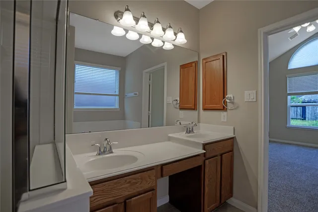 a bathroom with double vanity sinks a vanity a lamp and a mirror