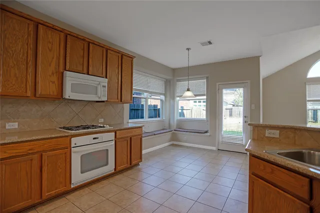 a kitchen with stainless steel appliances granite countertop a stove a sink and a microwave
