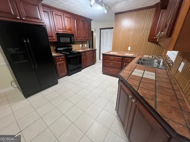 a kitchen with stainless steel appliances a sink a stove a refrigerator a sink a washer dryer and cabinets