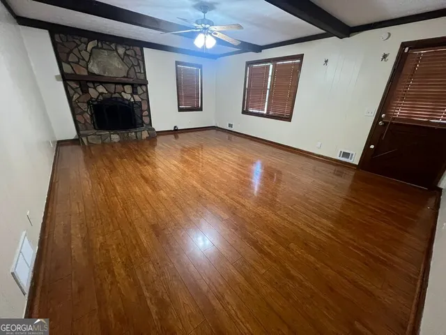 a view of an empty room with wooden floor and a ceiling fan