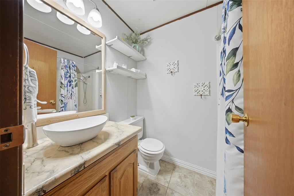 610 Walter Road Gainesville, TX 76240 - Photo 7 of 33 a spacious bathroom with a granite countertop sink toilet a mirror and shower