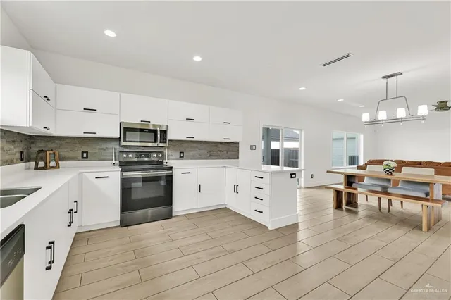 a kitchen with white cabinets stainless steel appliances and a window