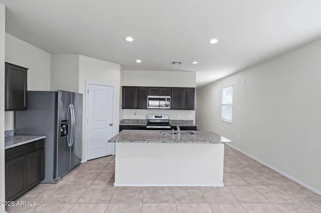 a kitchen with stainless steel appliances a sink a stove a microwave a refrigerator a window