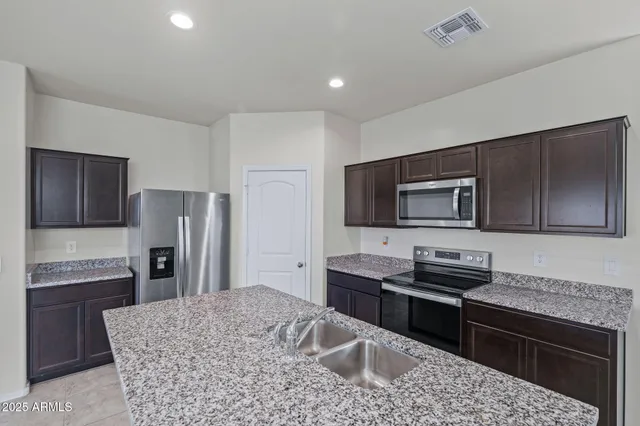 a kitchen with kitchen island stainless steel appliances a sink stove and refrigerator