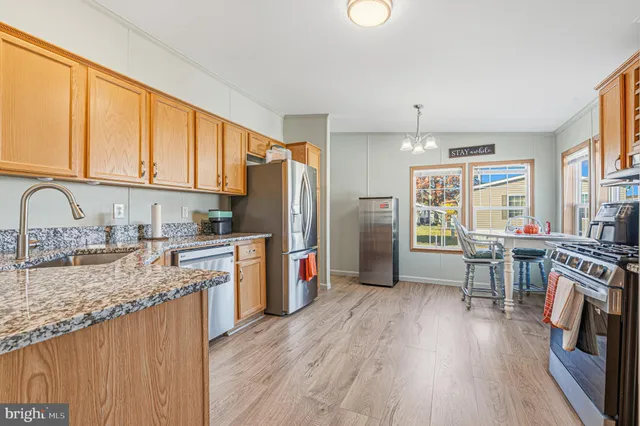 a kitchen with a refrigerator a stove top oven a sink dishwasher and wooden cabinets with wooden floor