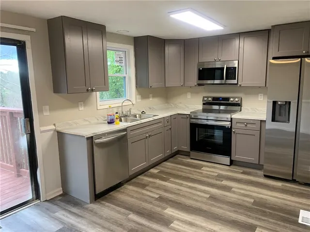 a kitchen with stainless steel appliances granite countertop a stove a sink dishwasher a refrigerator and a microwave oven with wooden floor