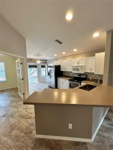 a view of kitchen with stainless steel appliances granite countertop a refrigerator a stove and a sink