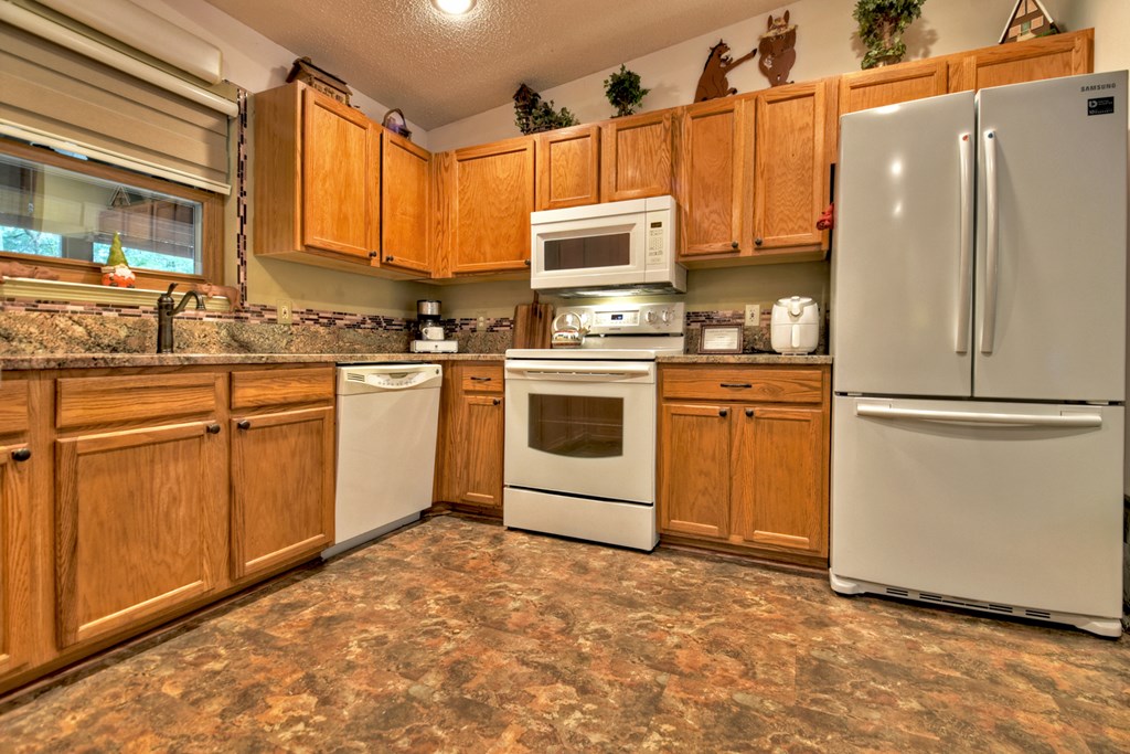97 Mill Creek Acres Blue Ridge, GA 30513 - Photo 26 of 33 a kitchen with stainless steel appliances granite countertop a refrigerator a stove a sink dishwasher and white cabinets with wooden floor