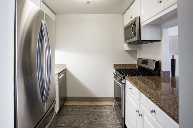 a kitchen with stainless steel appliances granite countertop a refrigerator and a stove