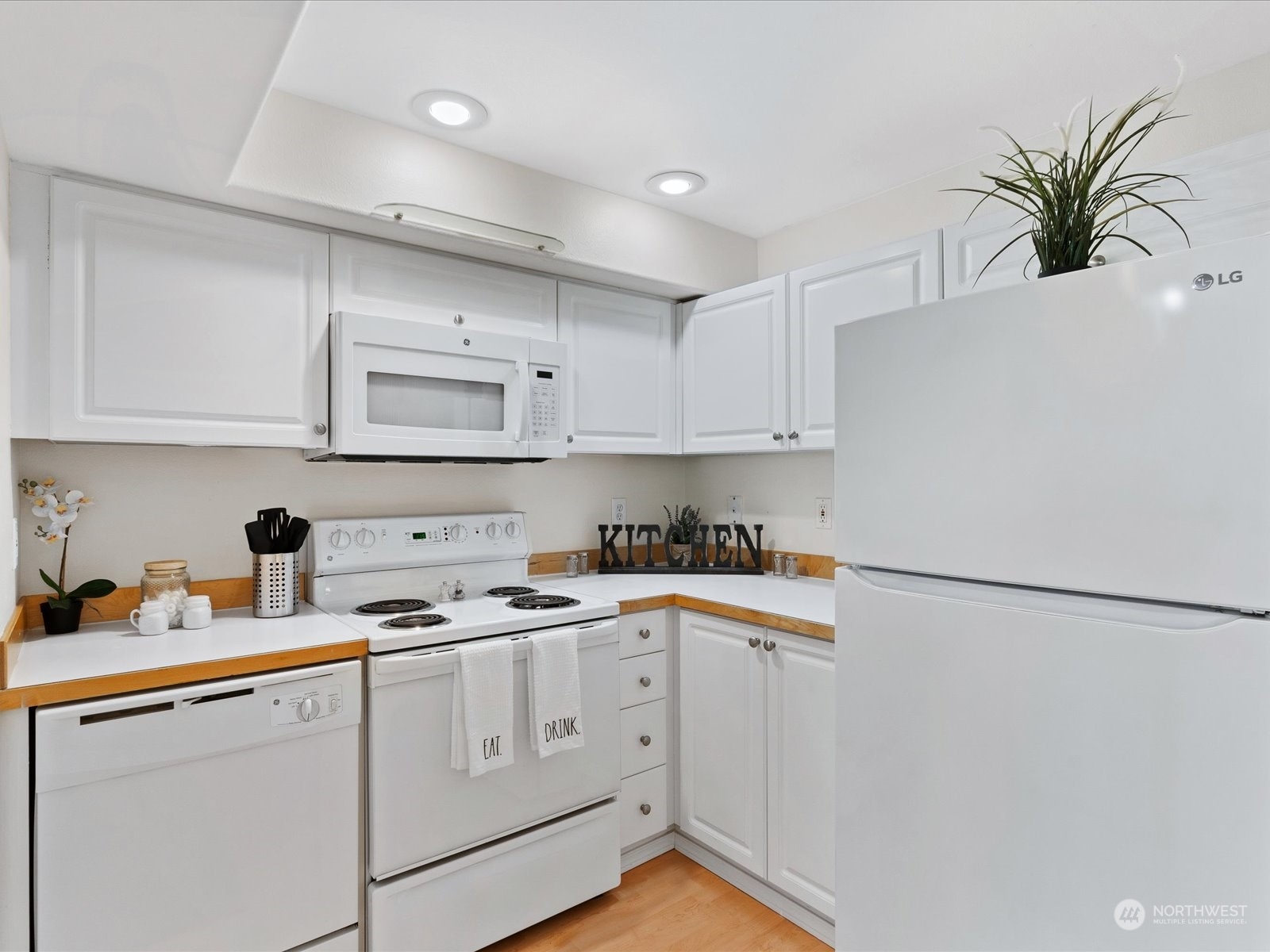 a kitchen with cabinets appliances a sink and a potted plant
