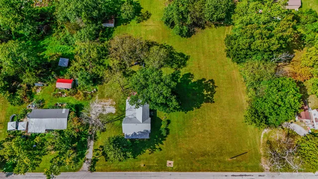 an aerial view of residential house with outdoor space and trees all around
