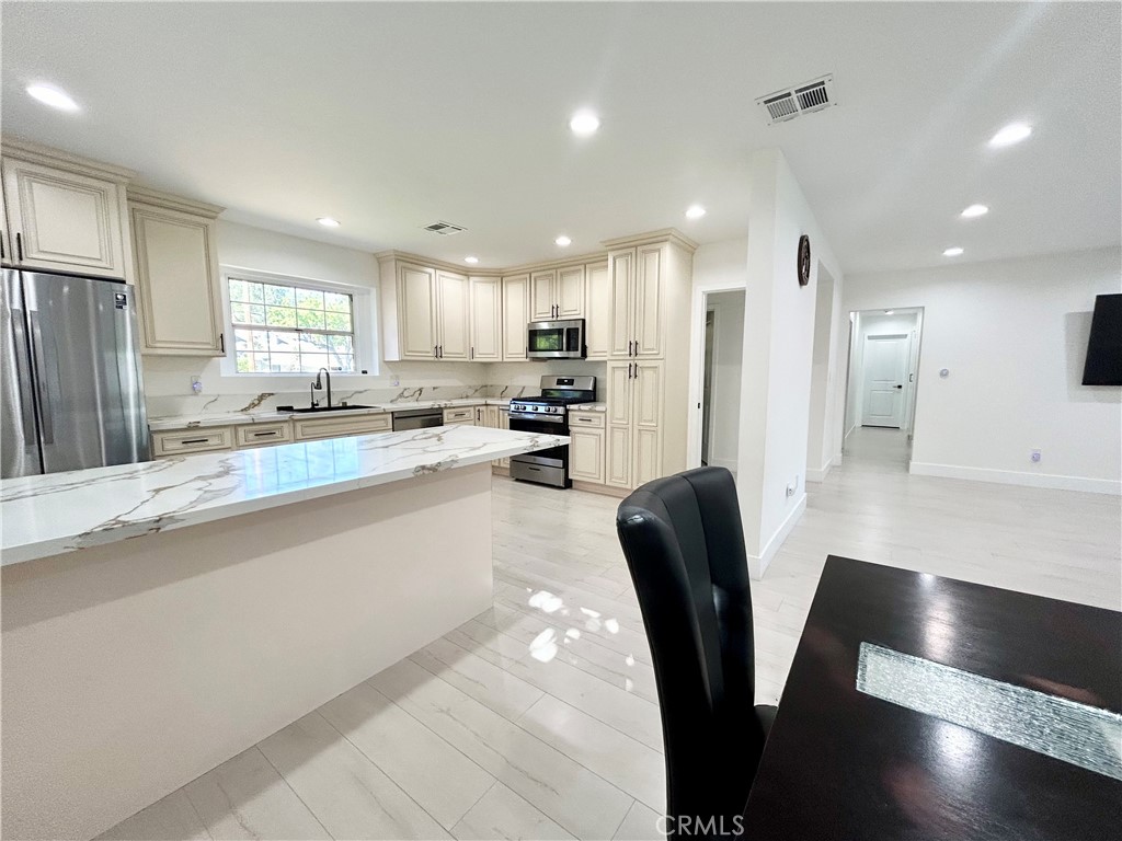 16754 Armstead Street Granada Hills, CA 91344 - Photo 4 of 28 a kitchen with stainless steel appliances granite countertop a refrigerator a sink a stove a dining table and chairs